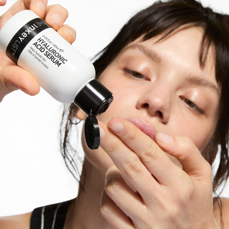 Person applying a bottle of Italey Hyaluronic Acid Serum to their face.