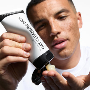 Model squeezing Oat Cleansing Balm on his hand