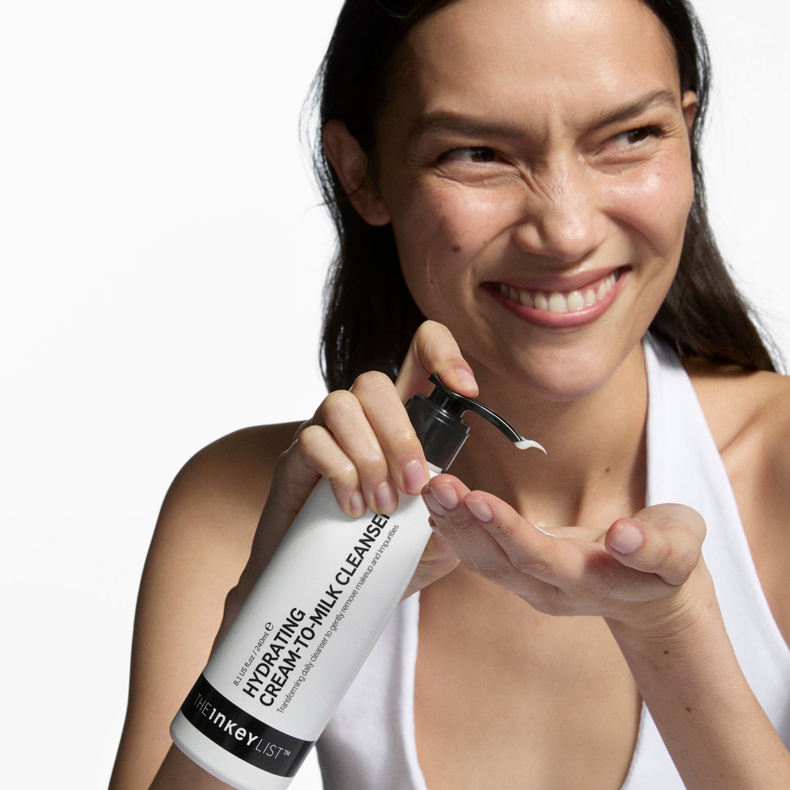 Woman holding a bottle of Inkey List skincare product with a white background