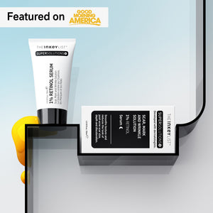 Scar, Mark & Wrinkle Solution tube and outer packaging on a black shelf against blue gradient background with yellow goop next to it