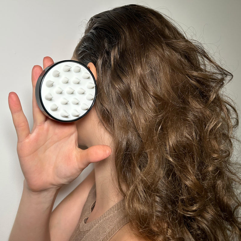woman with scalp massager in the shower