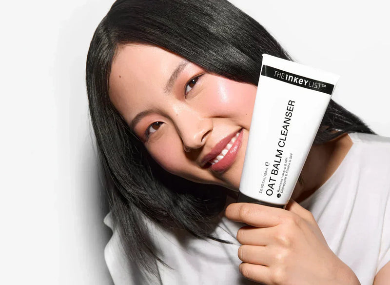 Woman holding a tube of Oat Cleansing Balm
