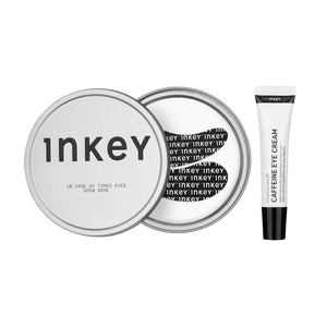 Inkey Timed Eyes primer set featuring a silver metal lid with black text, a matching silver container with a black heart design, and a white tube of caffeine eye cream with a black cap, all on a white background.