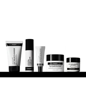 Five skincare products from The Inkeyist brand arranged in a row on a black surface against a white background. The products include an oat balm cleanser tube, Exosome Glow Complex, Advanced Retinal, Bio-Active Ceramide Eye Cream, and a Bio-Active Ceramide Moisturiser.