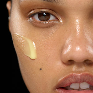 Close-up of a person's face with a skincare product applied to the cheek.