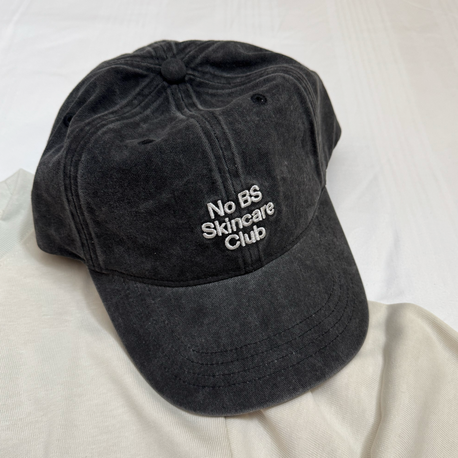 Black cap with 'No BS Skincare Club' text on a white background