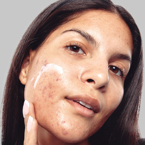 Model looking closely Into the camera with moisturizer on her face
