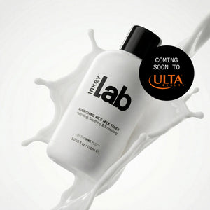 A white bottle of Inkey Lab Nourishing Rice Milk Toner with a black cap, set against a white background with a milk splash graphic. A black circular badge on the right reads 'COMING SOON TO ULTA BEAUTY'.