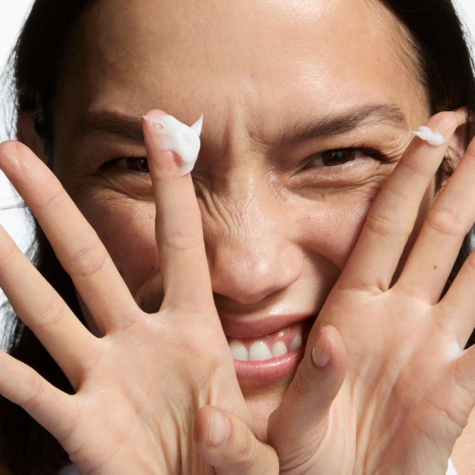 Woman applying cream to her face with a close-up view.