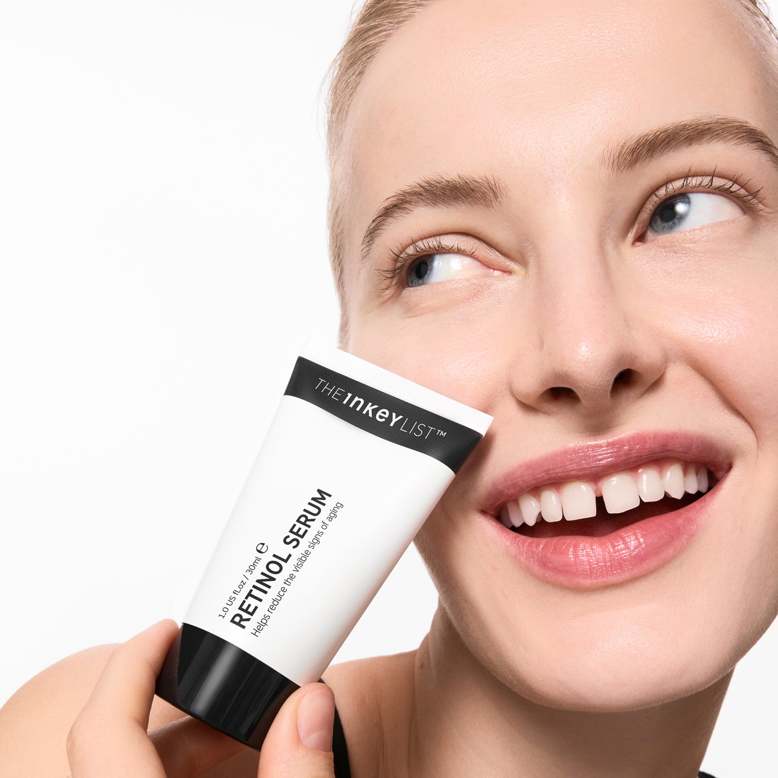 Mujer sosteniendo suero de retinol con un fondo liso