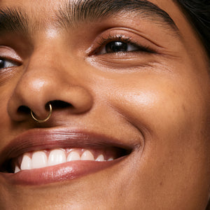 Close-up of a person's face with a nose ring, smiling.