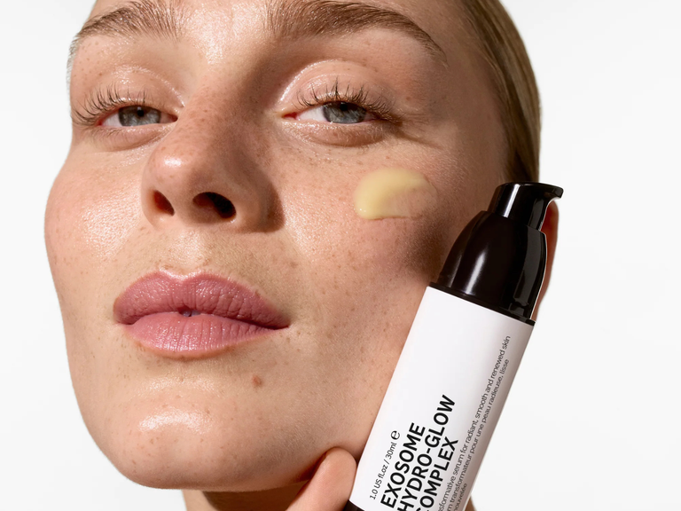 Woman applying a skincare product to her face with a close-up of the product.
