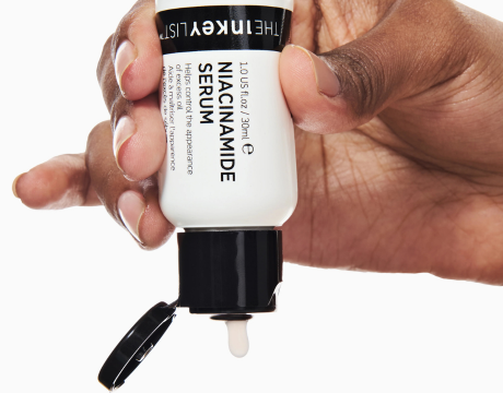 Hand holding a skincare serum bottle labeled 'The Linekery List' on a white background