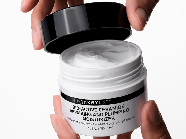 Jar of 'The Inkey List' moisturizer with cream being scooped out, held by a hand.