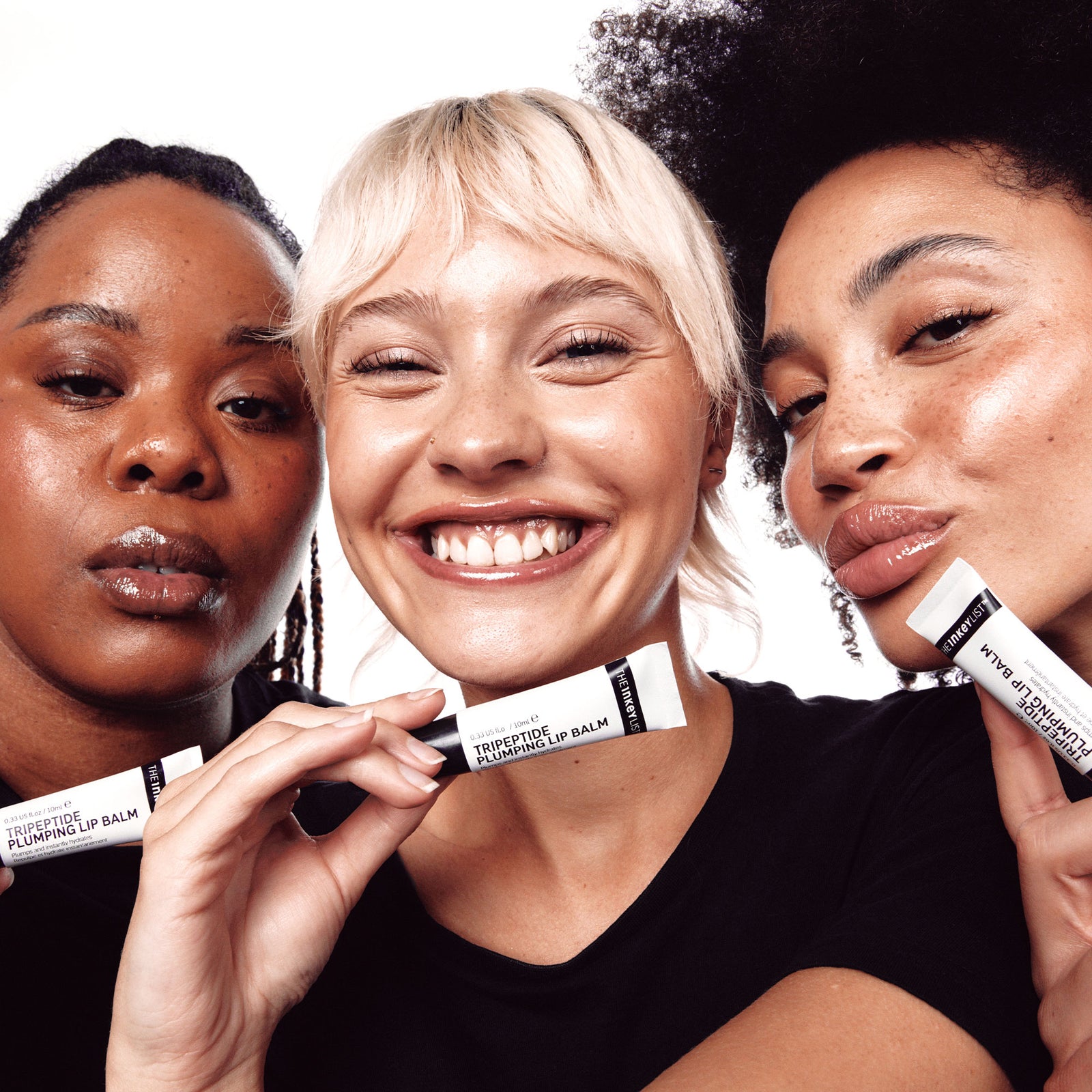 3 female models holding tubes of Tripeptide Plumping Lip Balm