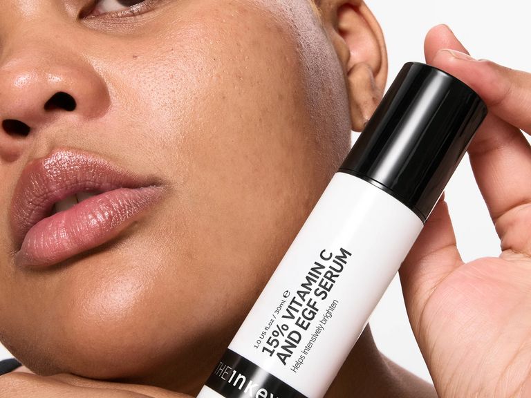 Person holding a skincare serum close to their face