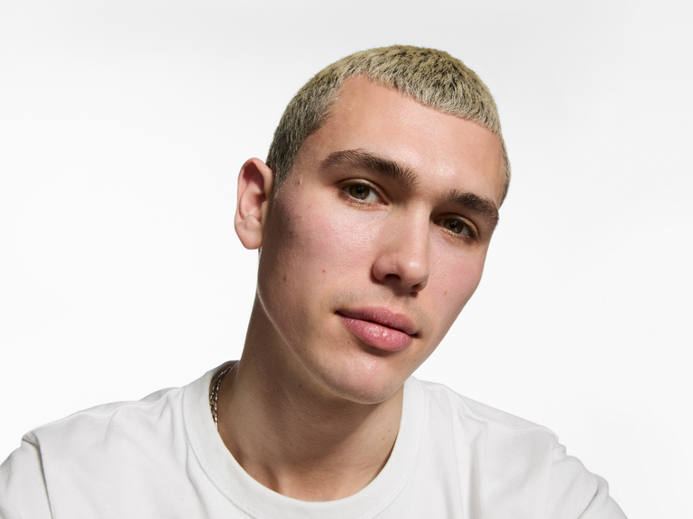 Person with platinum blonde hair wearing a white shirt on a white background
