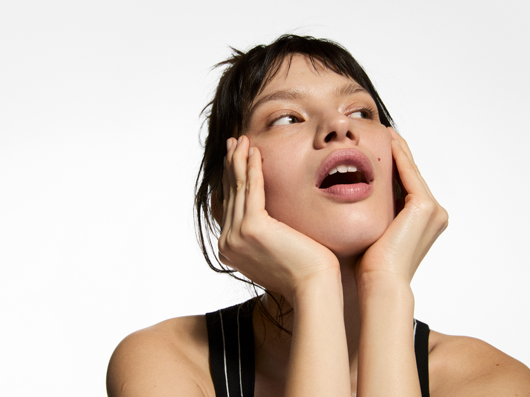 Woman with hands on face against a white background