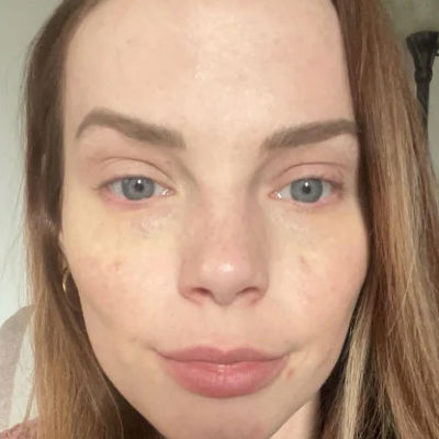 A close-up selfie of a woman's face showing her skin texture, freckles, and natural makeup.