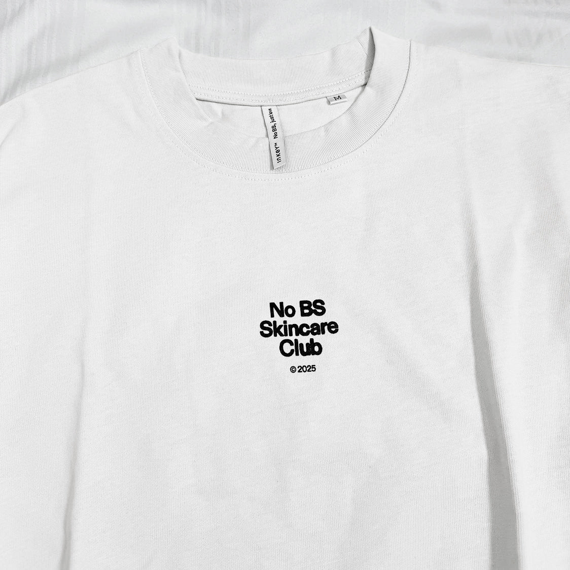 White t-shirt with 'No BS Skincare Club' text on a white background