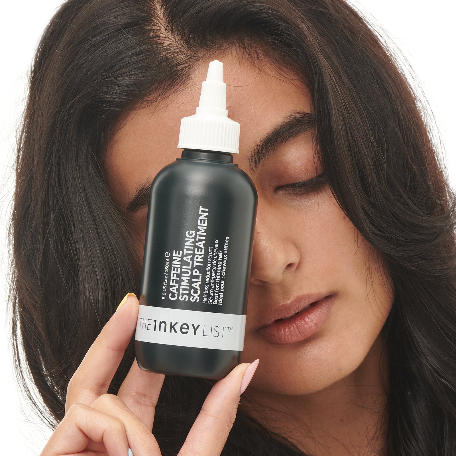 Caffeine stimulating scalp treatment bottle with model holding it