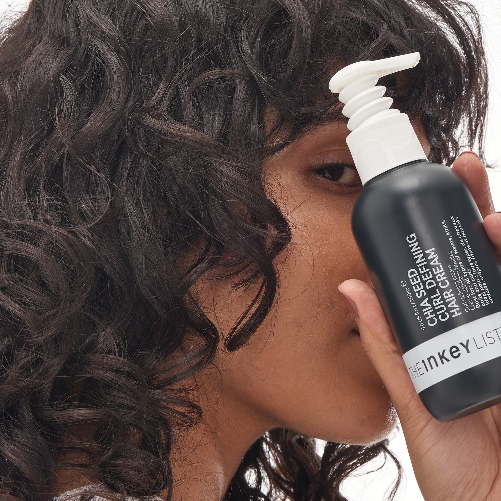 Chia seed curl defining hair treatment bottle with model holding it
