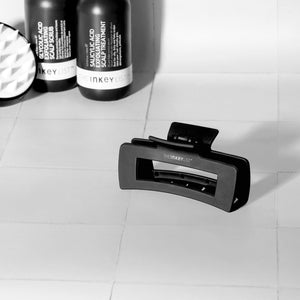 Image of The INKEY List Hair Clip in a tiled bathroom, paired with our haircare products and the Scalp Massager to showcase a great haircare routine