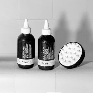 Image of The INKEY List Scalp Massager sitting next to INKEY haircare products in a white tiled bathroom as part of a great haircare routine